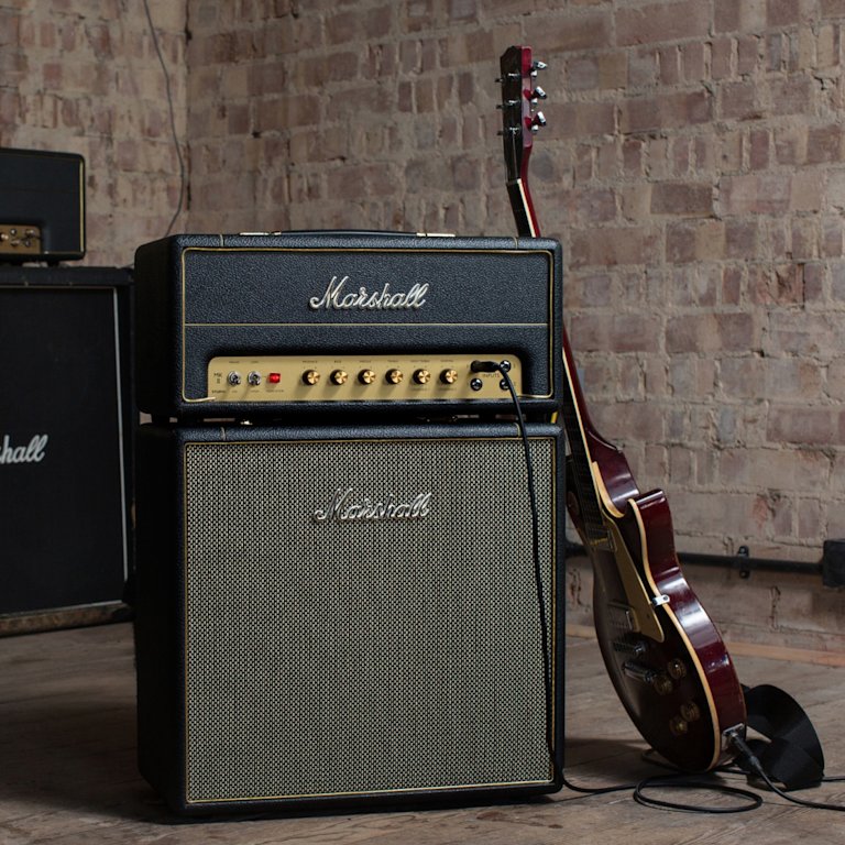 Junto a una pared de ladrillo se exponen amplificadores y guitarras Marshall Studio Vintage Head.
