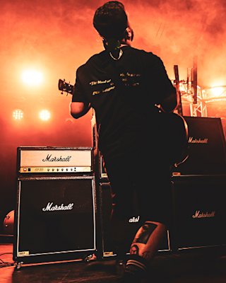 A band performing live on stage in front of Marshall amplifiers