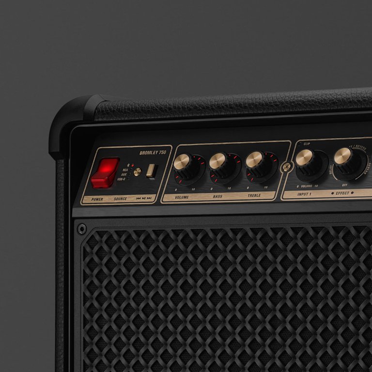 Close-up of a Marshall Bromley 750 party speaker with a black textured surface, featuring control knobs for volume, bass, treble, input jacks, and a red power switch.