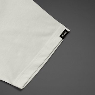 Close-up of the sleeve of a white T-shirt with a small black Marshall label on the hem, displayed against a dark gray background.
