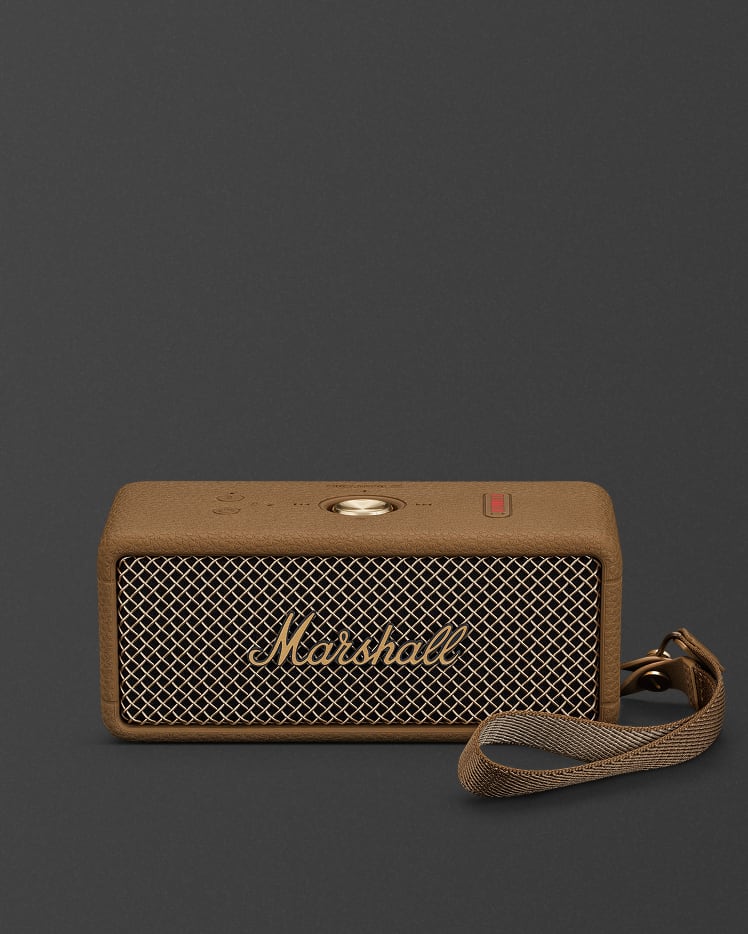 A Marshall Emberton III Brown portable Bluetooth speaker with a gold control knob, mesh front grille, logo, and attached strap, set against a dark background.