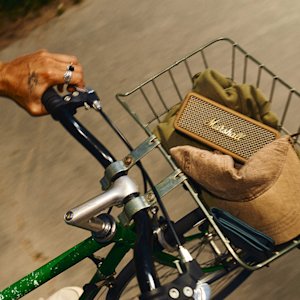 A brown Emberton III speaker inside a bicycle basket