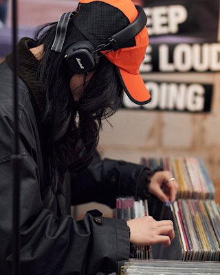 A person browsing vinyls with Marshall headphones on