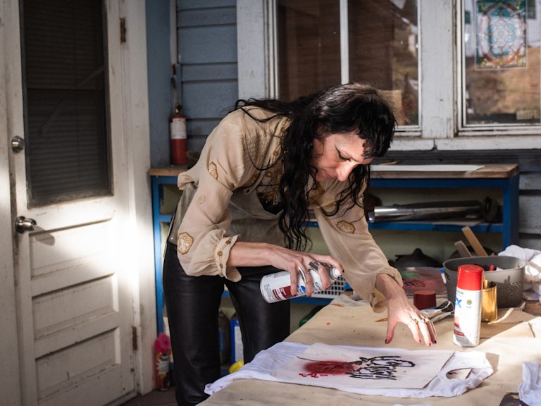 Zumi Rosow is painting a piece of paper on a table.