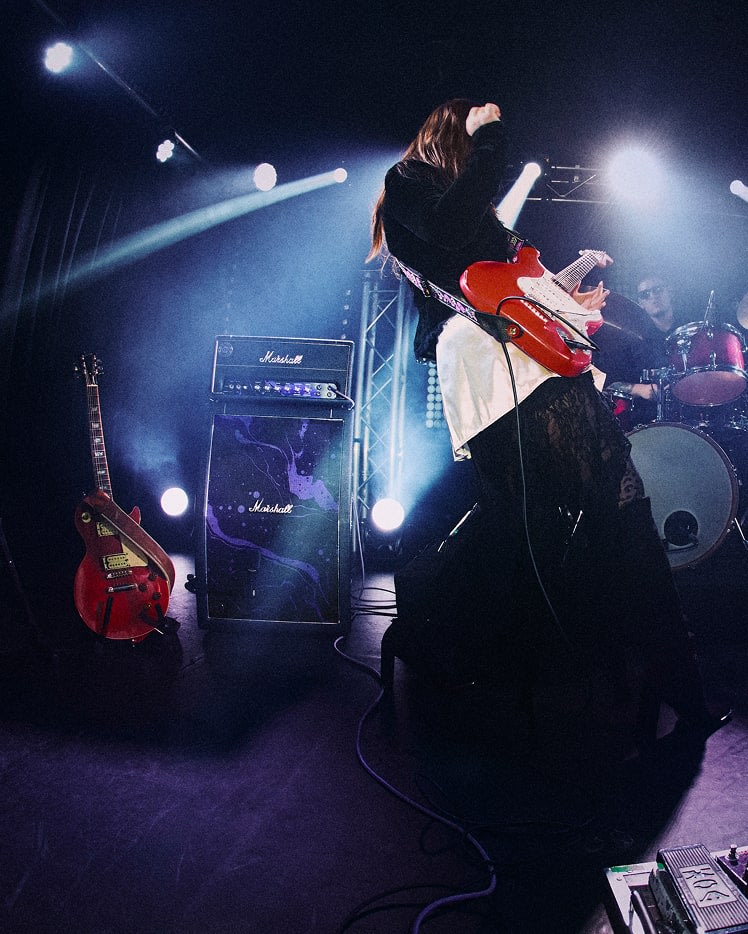 A guitarist plays electric guitar on stage, with Studio JMH Half Stack Hendrix Edition in the background.