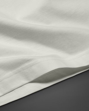 Close-up of a white cotton t-shirt, showing stitching detail along the hem.
