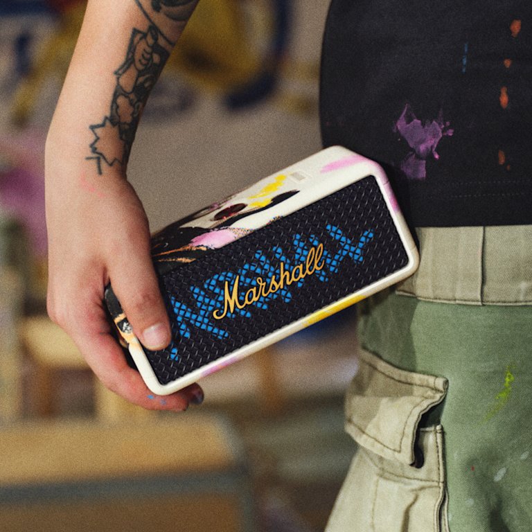 Una persona sostiene un altavoz portátil Marshall Emberton III Lunar New Year Edition 2026 decorado con pintura de colores.
