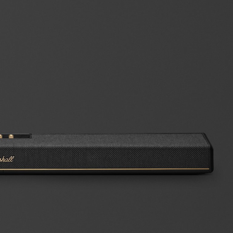 The Marshall Heston 120, a sleek black soundbar with gold accents and a visible mesh grille, is elegantly displayed against a dark gray background.