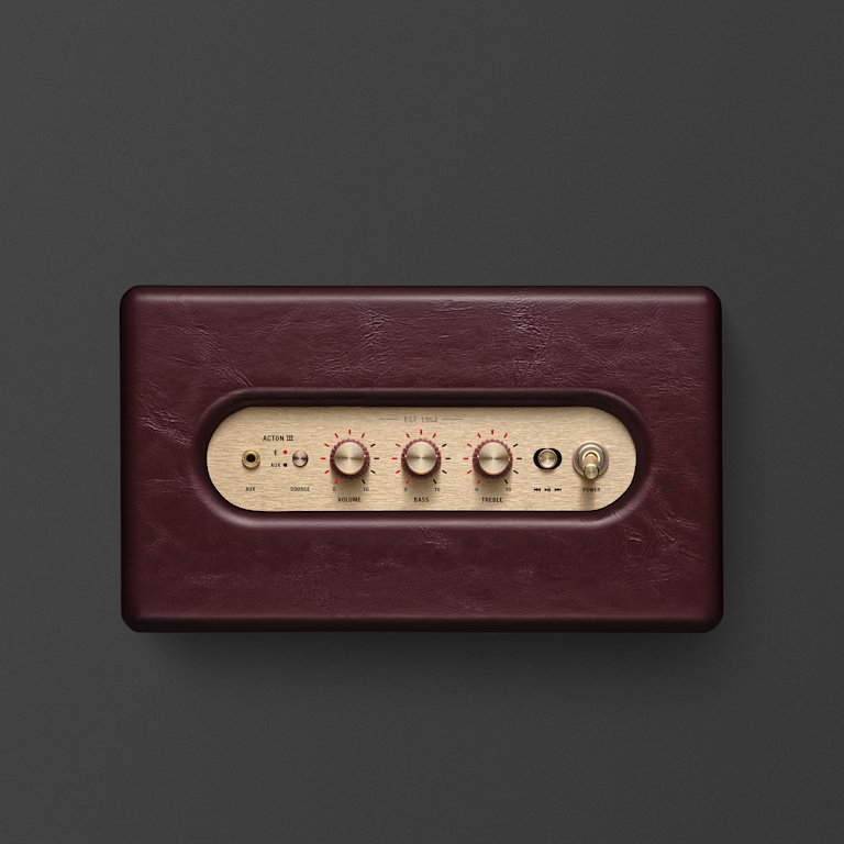 A close-up of a Marshall Acton III Burgundy speaker, showing control knobs and switches on a gold panel.