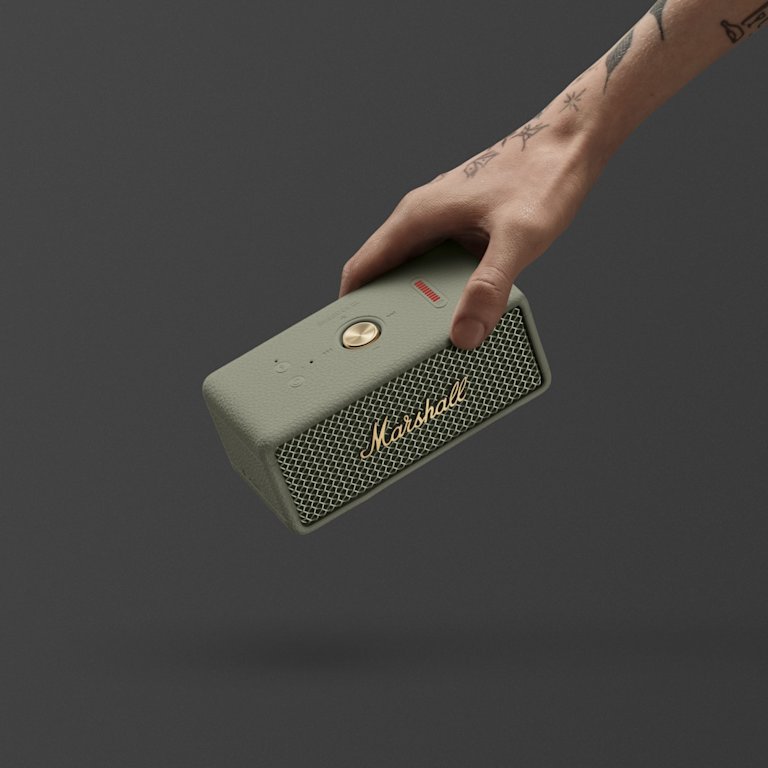 A hand holding a Marshall Emberton III Sage portable Bluetooth speaker against a dark background.