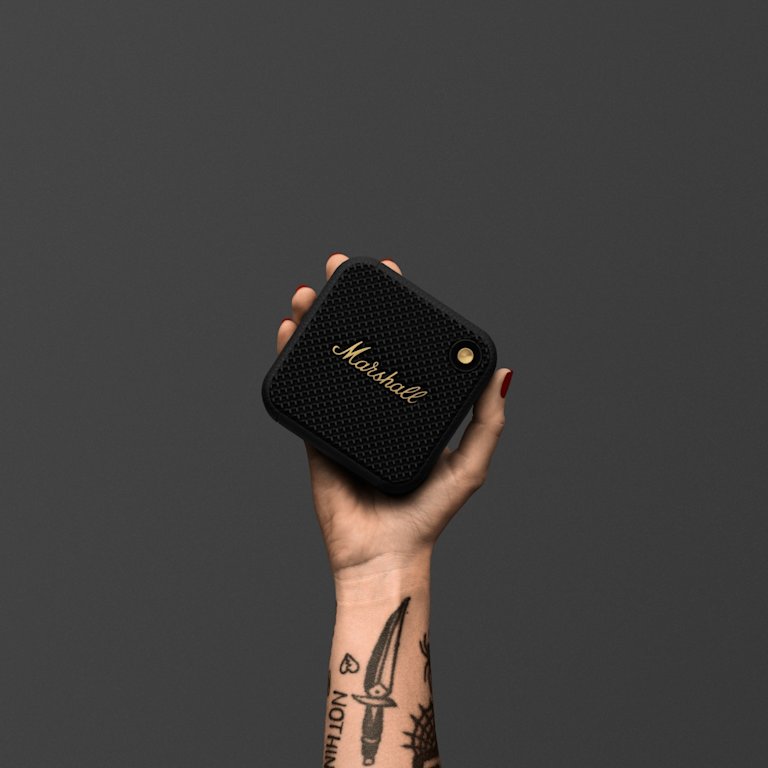 A woman holding a Marshall portable speaker with a tattoo on it.