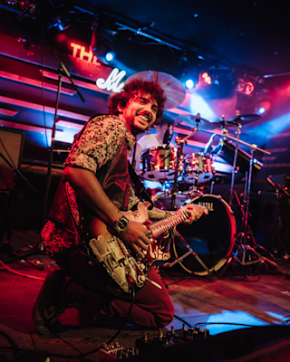 A person is joyfully playing the guitar on stage