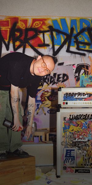 A man is standing bent over in a graffiti environment with an amp, featuring the Lunar New Year 2026 edition.