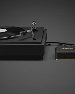A black turntable playing a vinyl record is connected by a cable to Marshall Heddon.