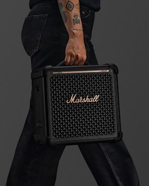 Person with tattoos on their arm carrying Bromley 150 Black and Brass by its top handle.