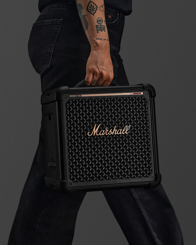 Person with tattoos on their arm carrying Bromley 150 Black and Brass by its top handle.