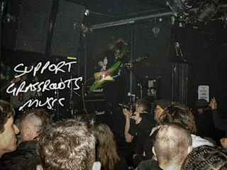 A guitar player playing guitar in a GIF with words 'Support Grassroots music'