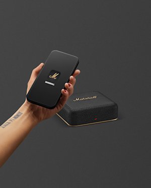 A hand holding a smartphone, positioned above a Marshall Heddon.