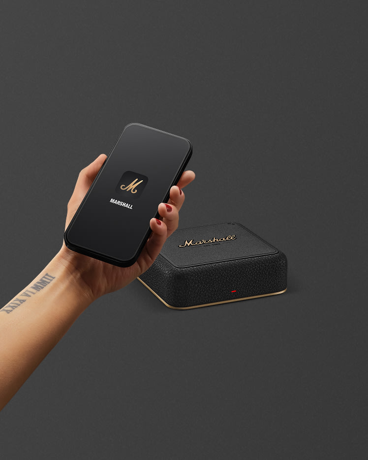 A hand holding a smartphone, positioned above a Marshall Heddon.