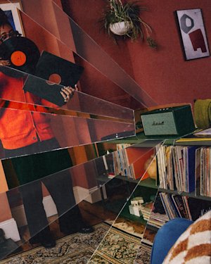 A person holding a vinyl record standing in a living room with Marshall Stanmore IV Black speaker and vinyl collection.
