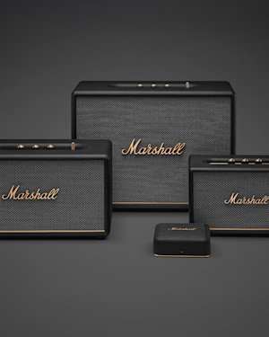 Three black Marshall speakers and Heddon displayed on a gray surface against a gray background.