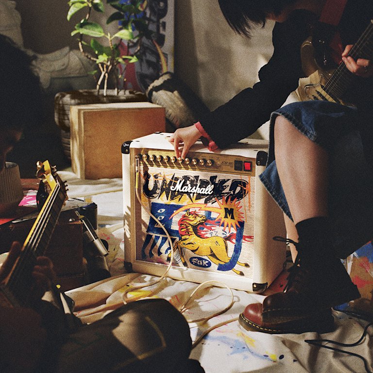 Person adjusting the knobs on a Marshall Studio 900 Combo Lunar New Edition 2026, surrounded by various objects and cables on the floor.
