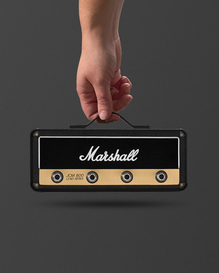 A hand holds a Jack Rack JCM800: Reissue by its handle against a plain, dark background.