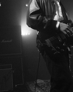 A black and white image of a guitar playing guitar under the spotight