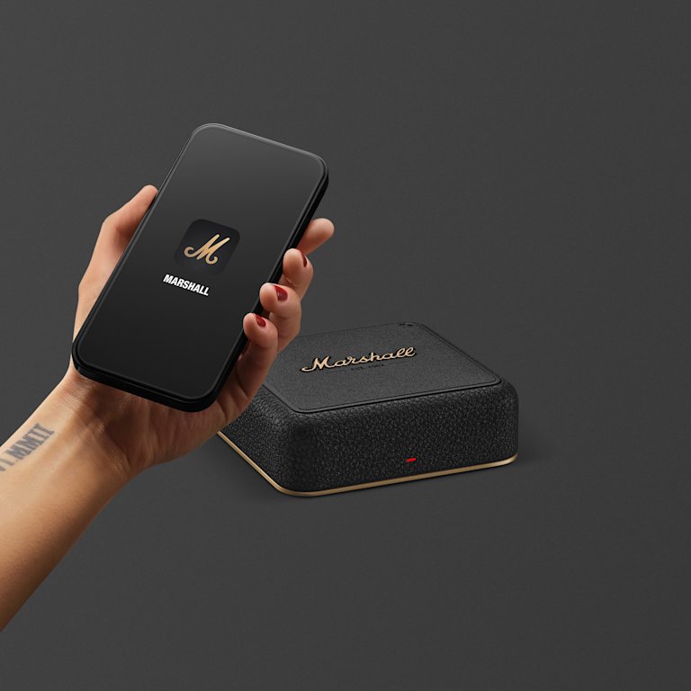 A hand holding a smartphone, positioned above a Marshall Heddon.