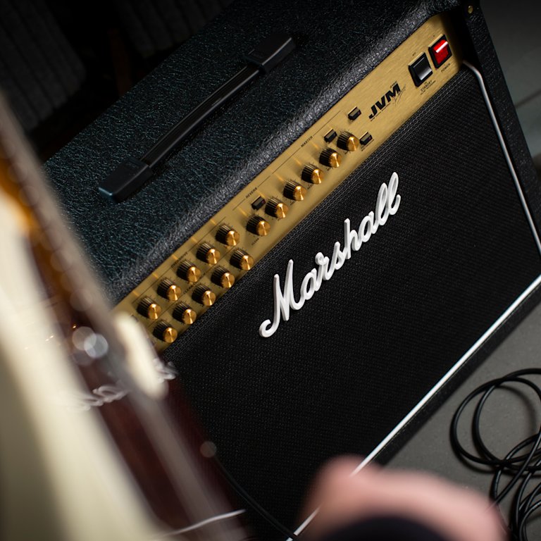 A person with a guitar next to the JVM215C combo amp