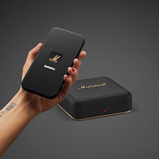 A hand holds a black smartphone with a Marshall logo next to Heddon.