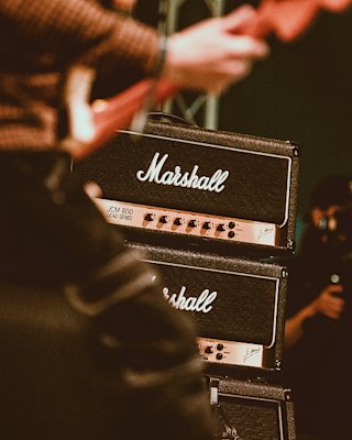 A person playing an electric guitar in front of an amplifier