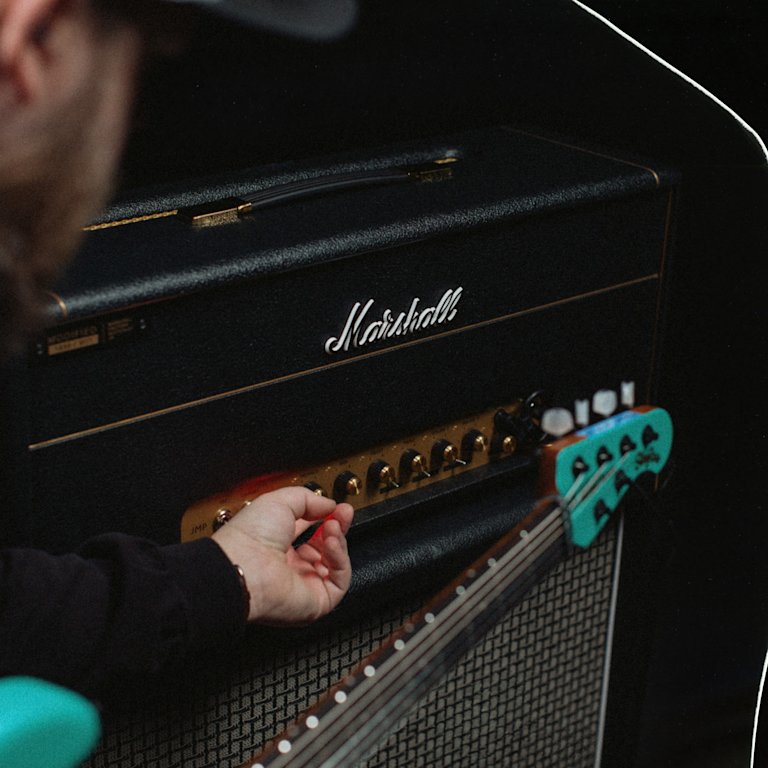 A person adjusting the control knobs in the front of the 1959 Modified amp