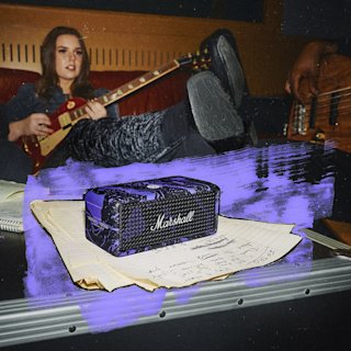 A guitar player in a room next to the Emberton III Hendrix Edition