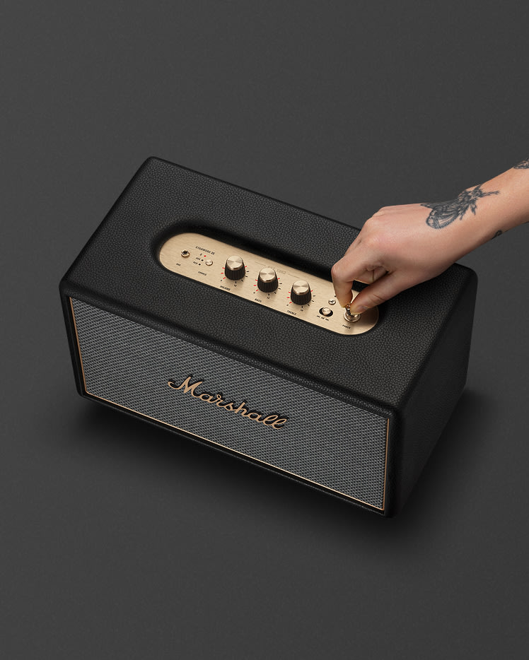 A hand with a tattoo switches power switch on Marshall Stanmore IV Black speaker.