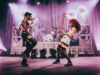 Nova Twins playing on stage with a purple lightning