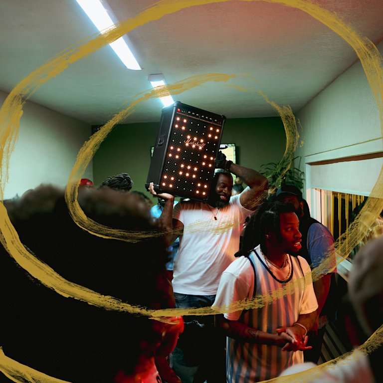 A man in a crowded room, raising the Marshall Bromley 750 party speaker.