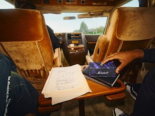 Marshall Emberton III Hendrix Edition speaker on a car console next to an open notebook with handwritten notes.