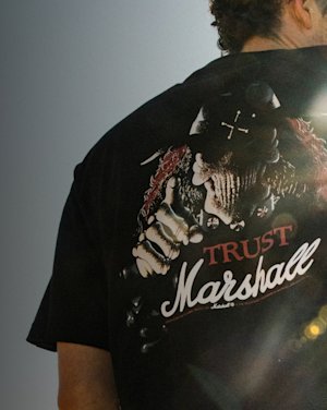 A person wearing a black Marshall t-shirt with a trust Marshall print