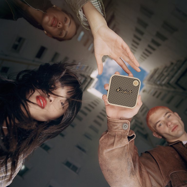 A group of people holding up a Marshall WILLEN CREAM wireless speaker.