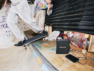 Stockwell III Black and Brass on an indoor skateboard ramp indoors, next to a charging smartphone.