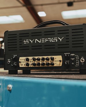 Une tête d'amplificateur de guitare Synergy avec un module de préampli Marshall JCM 800 installé sur une surface bleue dans un environnement intérieur.