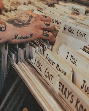 A person browsing vinyl records wearing a Marshall tattoo
