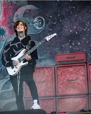 A person playing an electric guitar with amps in the background