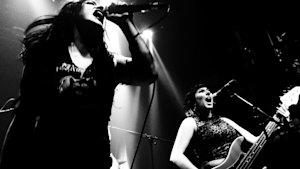 Two persons singing on stage in black and white