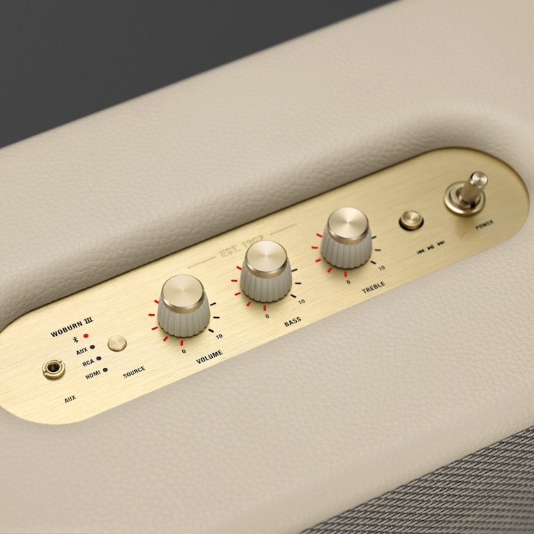 A close up of a Marshall Woburn III Cream speaker with gold buttons.