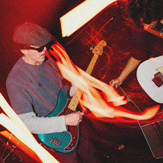 A person playing a blue electric guitar amid a vibrant light show