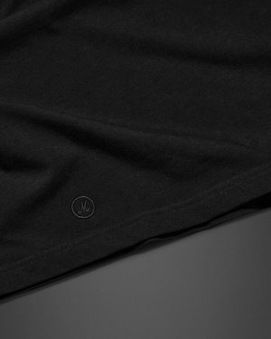 A close-up of a black fabric with a small circular "Marshall" embroidered logo near the edge, displayed on a smooth dark surface.