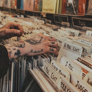 Someone holding and reading the cover of a vinyl in a record store
