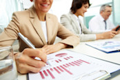 Woman using pen to write on top of bar charts